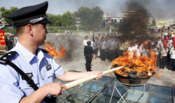 A Chinese policeman lights a cauldron filled with illicit drugs.